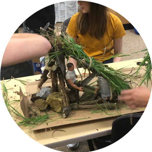 Image of adult students making a shelter out of environmental materials to solve a math and making challenge